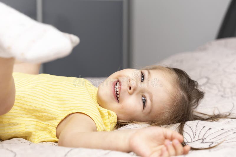 маленькая 4-летняя девочка в жёлтой футболке лежит на кровати стоковое фото маленькая 4-летняя девочка в жёлтой футболке лежит на кровати стоковое фото