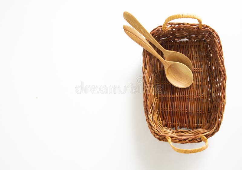 A small wicker basket with 2 wooden spoons on a beautiful white background. Copy space. Conceptual image. A small wicker basket with 2 wooden spoons on a beautiful white background. Copy space. Conceptual image.