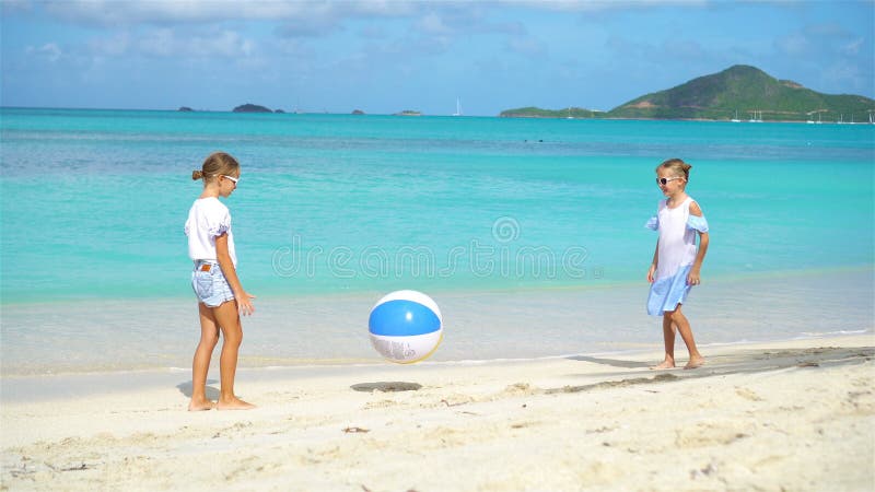 Маленькие прелестные девушки играя с шариком на пляже