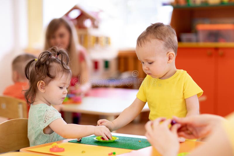 Маленькие ребята девушка и прессформа мальчика от теста игры в creche стоковое изображение Маленькие ребята девушка и прессформа мальчика от теста игры в creche стоковое изображение