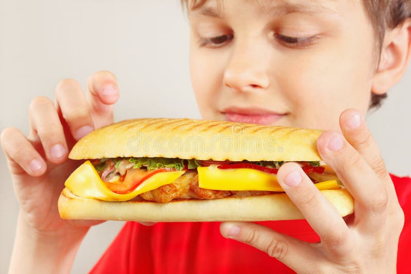 Маленький смешной мальчик с вкусным cheeseburger на белом конце предпосылки вверх стоковое изображение Маленький смешной мальчик с вкусным cheeseburger на белом конце предпосылки вверх стоковое изображение