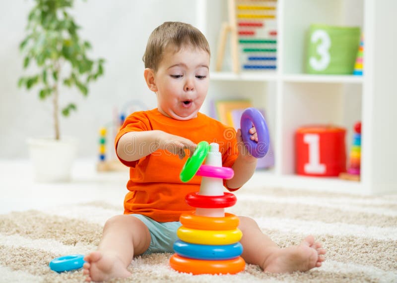 Baby toddler makes funny faces playing with educational toy on floor. Baby toddler makes funny faces playing with educational toy on floor