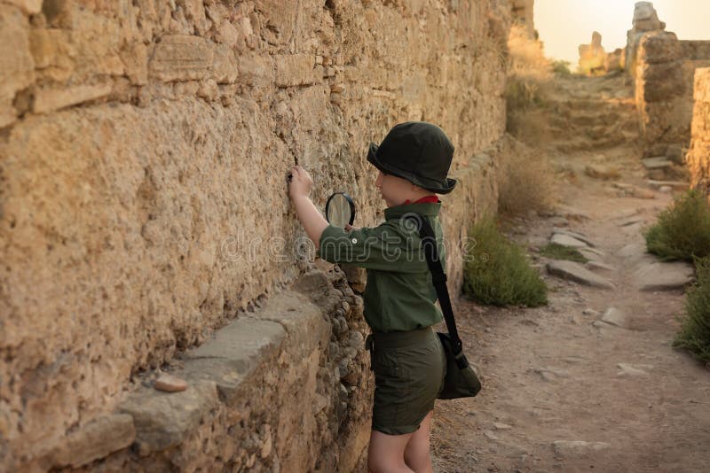 Boy archaeologist in khaki clothes studying the ruins of an ancient city. Diverse, non-traditional jobs concept. Boy archaeologist in khaki clothes studying the ruins of an ancient city. Diverse, non-traditional jobs concept.