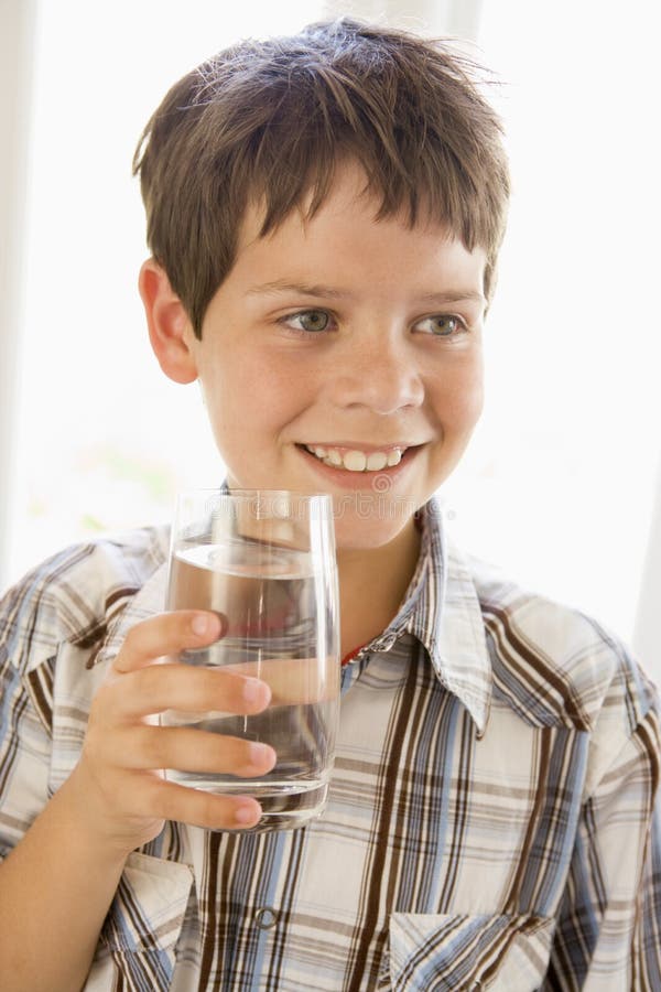 Portrait of boy drinking glass of water indoors by a window. Portrait of boy drinking glass of water indoors by a window