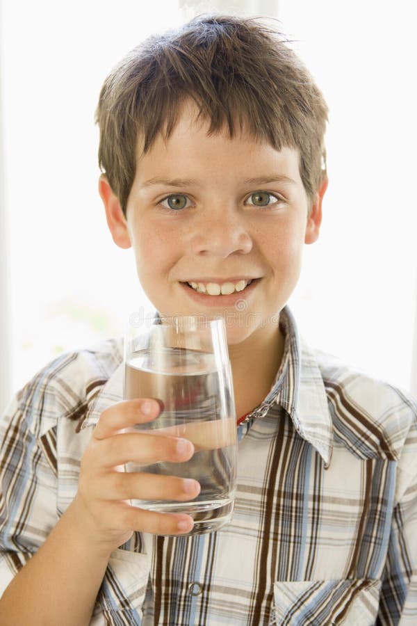 Portrait of boy drinking glass of water indoors by a window. Portrait of boy drinking glass of water indoors by a window