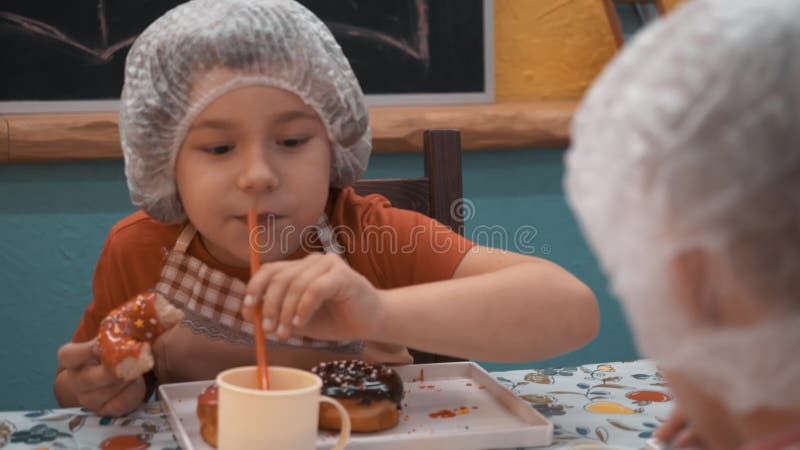Мальчик есть вкусный пончик после кулинарного мастер класса сток-видео