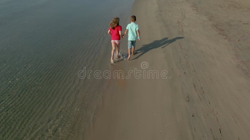 мальчик и девочка в купальнике бегают по берегу моря, держась за руки видеоматериал