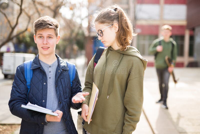 Teenage boy and girl discuss homework after college lessons on sunny spring day. Teenage boy and girl discuss homework after college lessons on sunny spring day