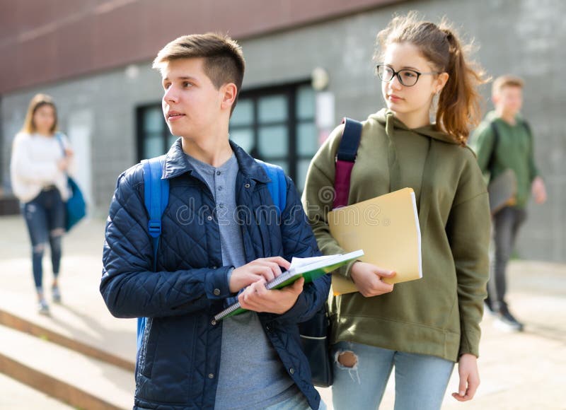 Teenage boy and girl discuss homework after college lessons on sunny spring day. Teenage boy and girl discuss homework after college lessons on sunny spring day