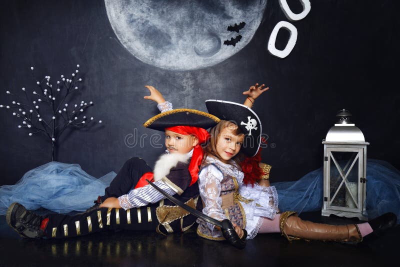 Мальчик и девушка в костюмах пирата удерживания halloween даты принципиальной схемы календара жнец мрачного счастливого миниатюрн стоковое фото rf Мальчик и девушка в костюмах пирата удерживания halloween даты принципиальной схемы календара жнец мрачного счастливого миниатюрн стоковое фото rf