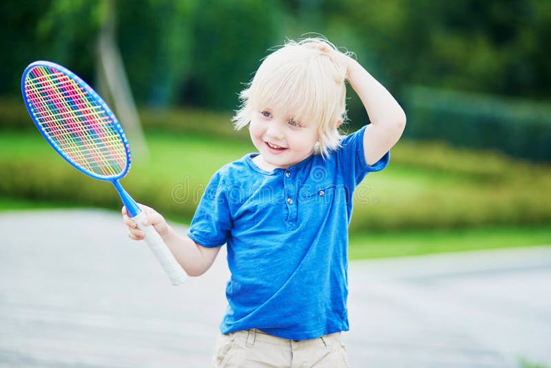 Adorable little boy playing badminton on the playground. Outdoor summer activities for kids. Adorable little boy playing badminton on the playground. Outdoor summer activities for kids