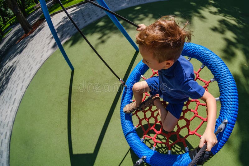 Мальчик на swing ребенка парка развлечений на счастливое игровое поле стоковые изображения rf