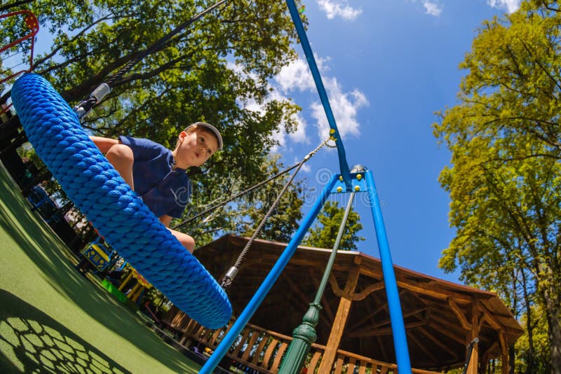 Мальчик на swing ребенка парка развлечений на счастливое игровое поле молодой стоковое изображение