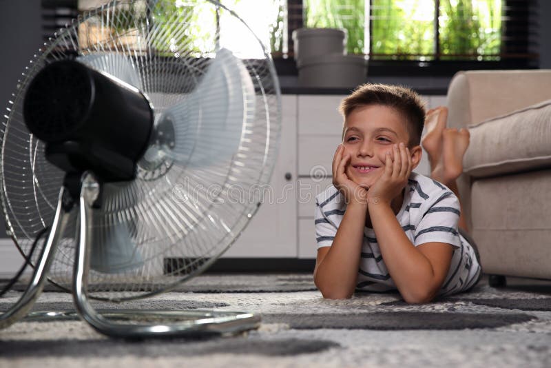 Little boy enjoying air flow from fan at home. Summer heat. Little boy enjoying air flow from fan at home. Summer heat