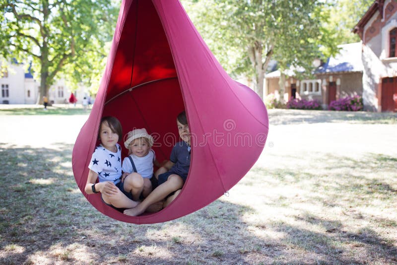 3 Мальчика детей качели в большом swing ткани в парке стоковая фотография rf
