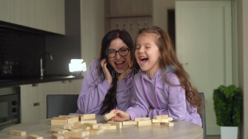 Мама и дочь сидели вместе за столом на кухне дома. Играй jenga настольных игр. Время весело вместе. видеоматериал