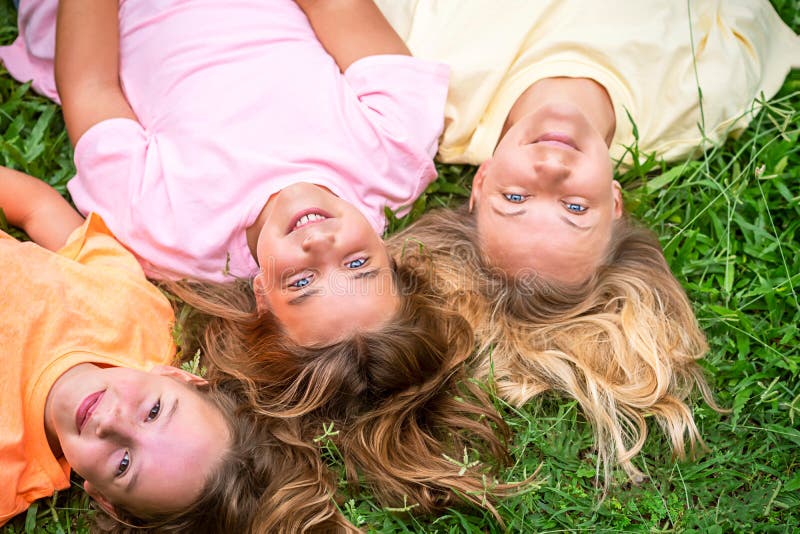 Happy loving family is resting in the park.  Mom and 2 daughters laugh.  Woman and children girls lie on their backs on the grass. Happy loving family is resting in the park.  Mom and 2 daughters laugh.  Woman and children girls lie on their backs on the grass