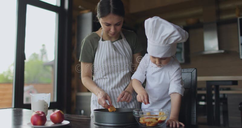 Мама и сын в апранах готовят яблочный пирог на кухне сток-видео
