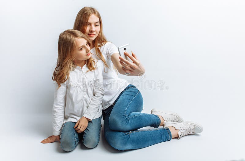 Мама или более старая сестра делают маленькую девочку selfie, счастливую семью, изолированную студию фото стоковая фотография rf