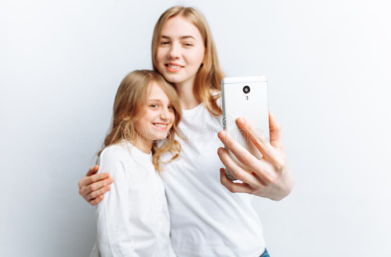 Мама или более старая сестра делают маленькую девочку selfie, счастливую семью, изолированную студию фото стоковые изображения rf