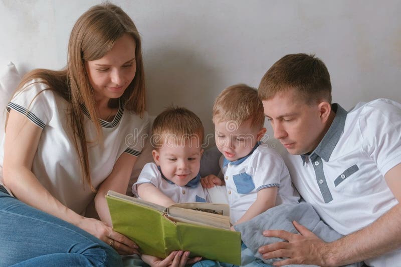 Мама семьи, папа и 2 брат-близнеца прочитали книги кладя на кровать Время чтения семьи стоковая фотография Мама семьи, папа и 2 брат-близнеца прочитали книги кладя на кровать Время чтения семьи стоковая фотография