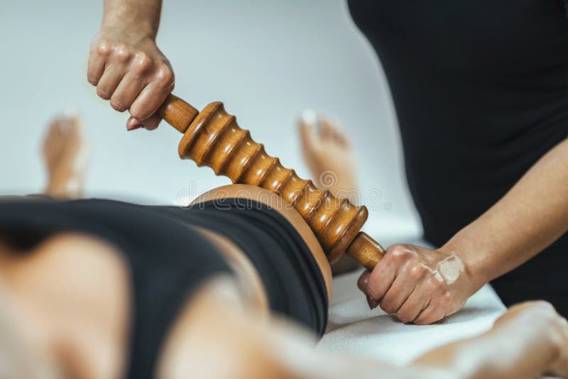 Rolling pin madero therapy massage. Female masseuse performing cellulite reduction treatment. Rolling pin madero therapy massage. Female masseuse performing cellulite reduction treatment