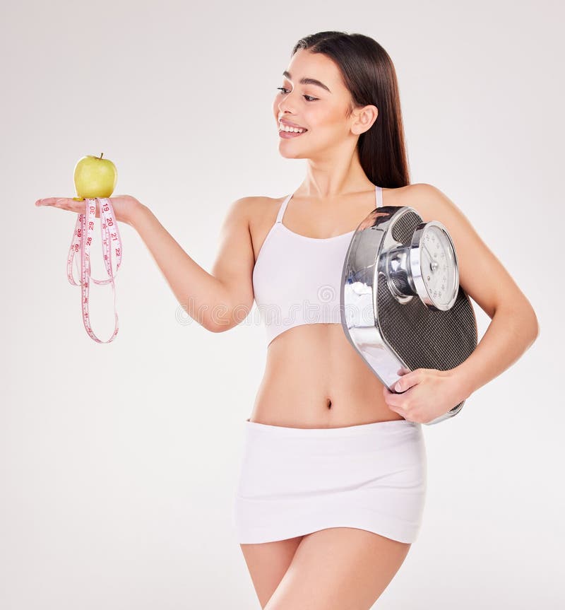 Scale, tape measure or happy woman with apple or smile for healthy snack, nutrition diet or digestion benefits. Body, lose weight and proud fitness model with fruits in studio on white background. Scale, tape measure or happy woman with apple or smile for healthy snack, nutrition diet or digestion benefits. Body, lose weight and proud fitness model with fruits in studio on white background.