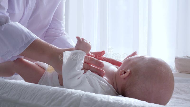 Материнская нежность, руки женщины делает массаж к newborn в комнате