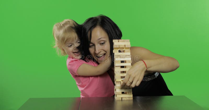 Мать и дочь играют jenga Ребенок вытягивает деревянные блоки от башни стоковые фотографии rf Мать и дочь играют jenga Ребенок вытягивает деревянные блоки от башни стоковые фотографии rf
