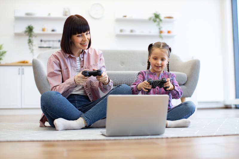 мать и дочь играют в видеоигры дома стоковое изображение rf
