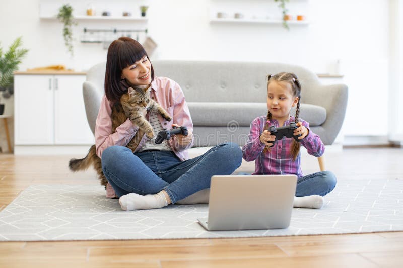 мать и дочь играют в видеоигры с котом на полу стоковое изображение rf