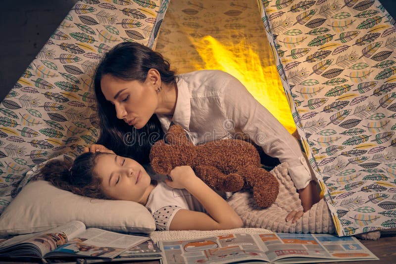Мать и ее дочь в шатре teepee с некоторыми подушками E стоковые фотографии rf Мать и ее дочь в шатре teepee с некоторыми подушками E стоковые фотографии rf