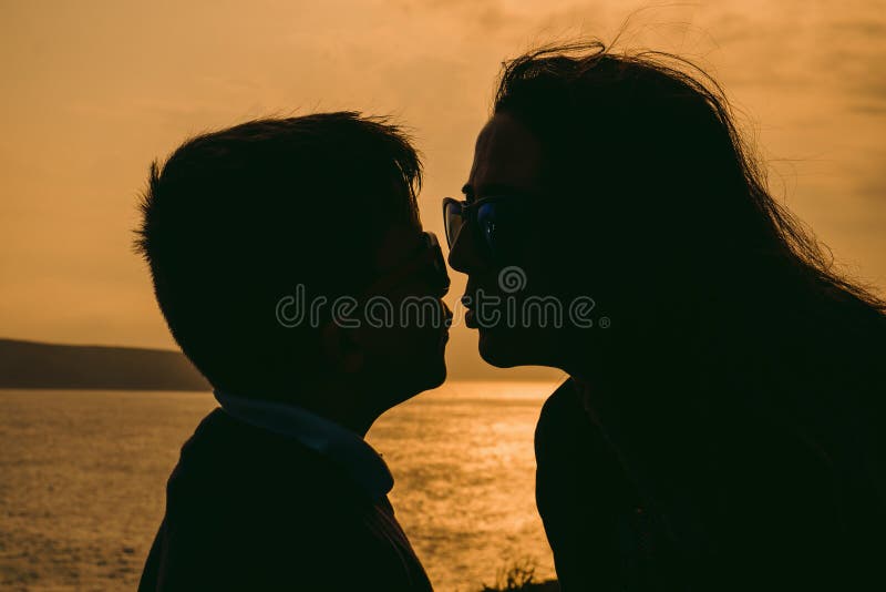 Mother and son on sunset holding by hands, outside isolated in front of a sunset in the sky on a summer day. Mother and son on sunset holding by hands, outside isolated in front of a sunset in the sky on a summer day