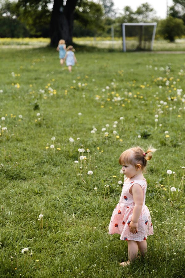 Mother having quality funny playing time with her baby girls at a park blowing dandelion - Young blonde hippie - Daughters wear similar dresses with strawberry print - Family values - 1, 2, 6 year old children on a sunny spring day. Mother having quality funny playing time with her baby girls at a park blowing dandelion - Young blonde hippie - Daughters wear similar dresses with strawberry print - Family values - 1, 2, 6 year old children on a sunny spring day