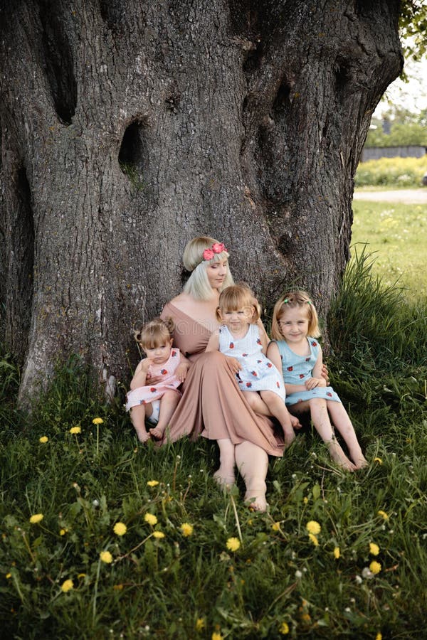 Mother having quality funny playing time with her baby girls at a park blowing dandelion - Young blonde hippie - Daughters wear similar dresses with strawberry print - Family values - 1, 2, 6 year old children on a sunny spring day. Mother having quality funny playing time with her baby girls at a park blowing dandelion - Young blonde hippie - Daughters wear similar dresses with strawberry print - Family values - 1, 2, 6 year old children on a sunny spring day