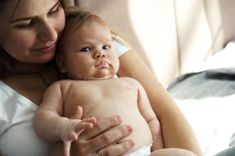 Мать с ее newborn сыном кладет на кровать в лучах солнечного света стоковое изображение rf Мать с ее newborn сыном кладет на кровать в лучах солнечного света стоковое изображение rf