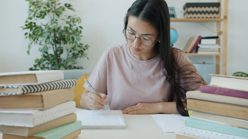 медленное движение внимательного студента, пишущего эссе, сидящего за столом с книгами дома