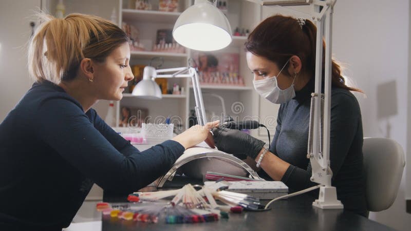 Мелкий бизнес - manicurist - мастер ногтя в медицинской маске делая профессиональный маникюр стоковые изображения Мелкий бизнес - manicurist - мастер ногтя в медицинской маске делая профессиональный маникюр стоковые изображения