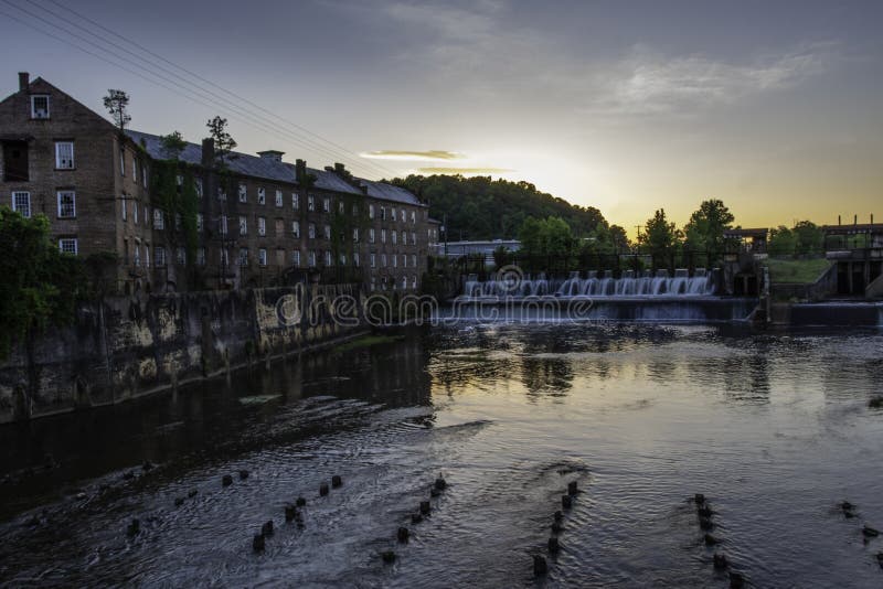 Prattville, Alabama/USA-May 2, 2019: The historic Cotton Gin Mill and water spillway for the mill pond on Autauga Creek at sunset. Prattville, Alabama/USA-May 2, 2019: The historic Cotton Gin Mill and water spillway for the mill pond on Autauga Creek at sunset