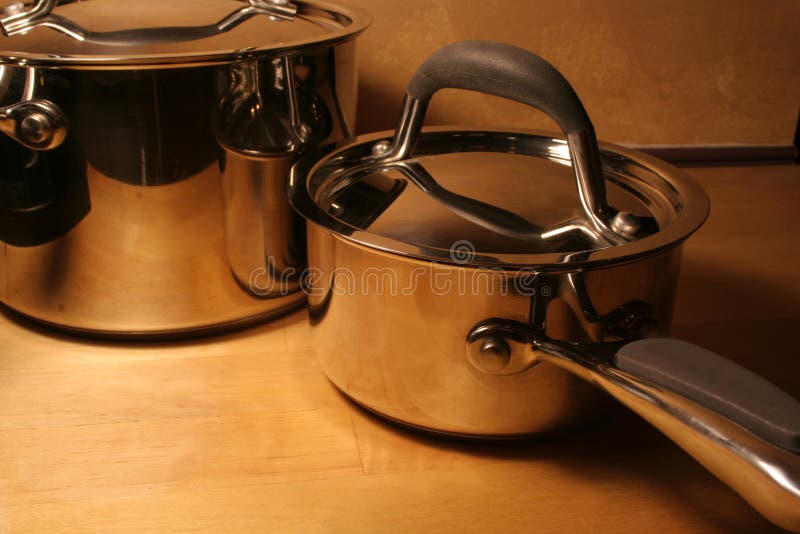 Metallic pots sitting on a wooden table. Metallic pots sitting on a wooden table.