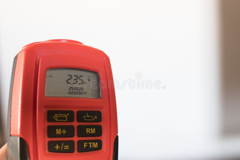 An orange laser meter pointed to the roof measuring 2.35 meters. Professional tools for architects. An orange laser meter pointed to the roof measuring 2.35 meters. Professional tools for architects