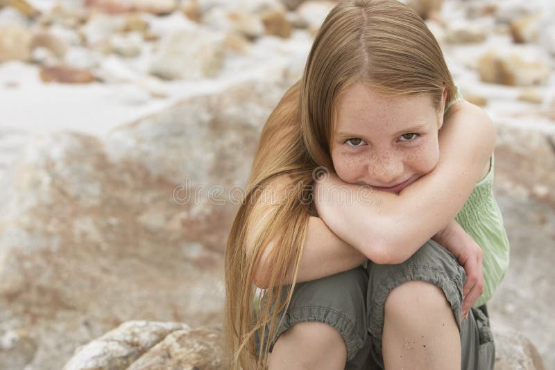 Милая девушка Preteen сидя на утесе стоковые изображения rf Милая девушка Preteen сидя на утесе стоковые изображения rf