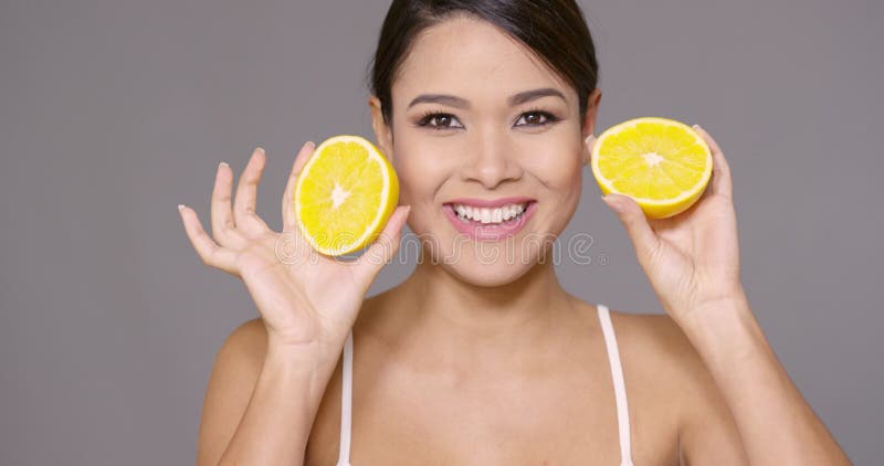 Милая молодая женщина держа уменьшанный вдвое свежий апельсин