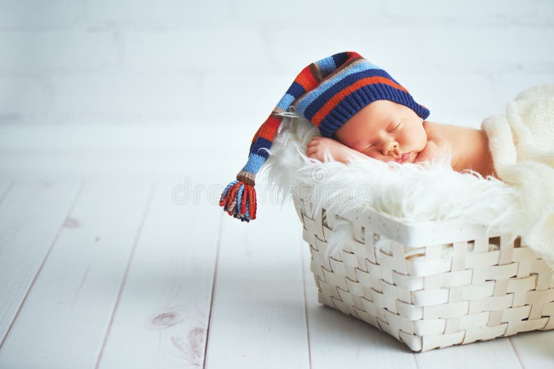 Милый newborn младенец в голубой крышке knit спать в корзине стоковое фото