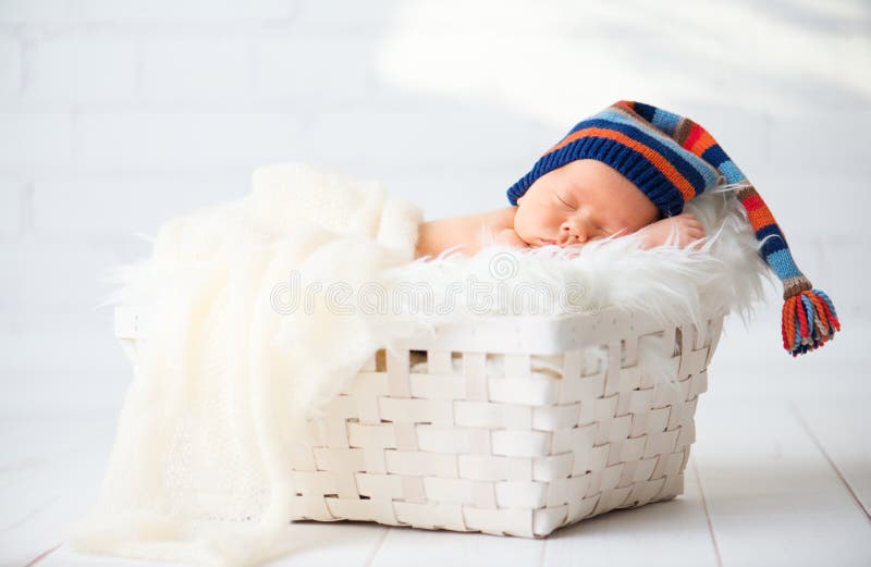 Милый newborn младенец в голубой крышке knit спать в корзине стоковое изображение rf