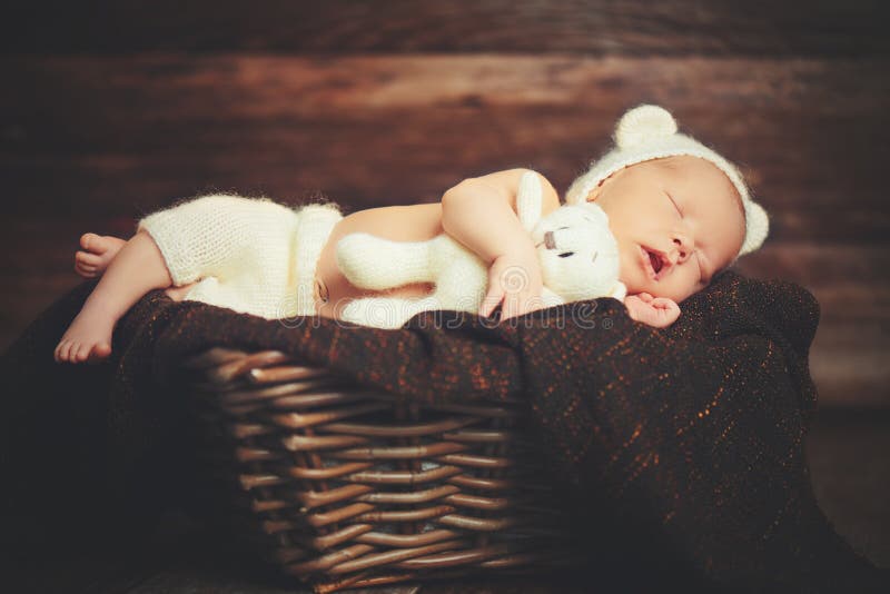 Милый newborn младенец в медведе шляпа спит в корзине с игрушечным игрушки стоковая фотография rf