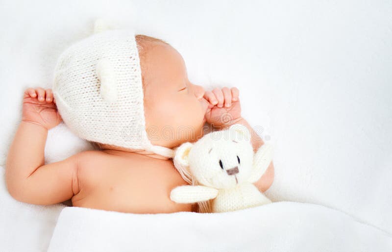 Милый newborn младенец в шляпе медведя спит с плюшевым медвежонком игрушки стоковые фото