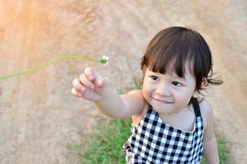 Cute little girl is sending flowers in her hand to someone the evening atmosphere with soft sunlight. Cute little girl is sending flowers in her hand to someone the evening atmosphere with soft sunlight