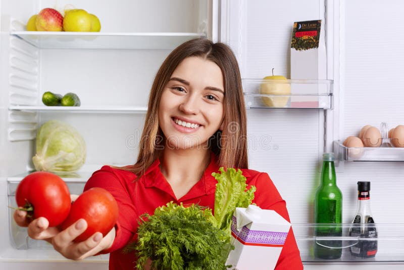 Милая домохозяйка с услаженным взглядом показывает продуктам что она купила в магазине ` s бакалейщика Красивая усмехаясь женщина стоковая фотография rf Милая домохозяйка с услаженным взглядом показывает продуктам что она купила в магазине ` s бакалейщика Красивая усмехаясь женщина стоковая фотография rf