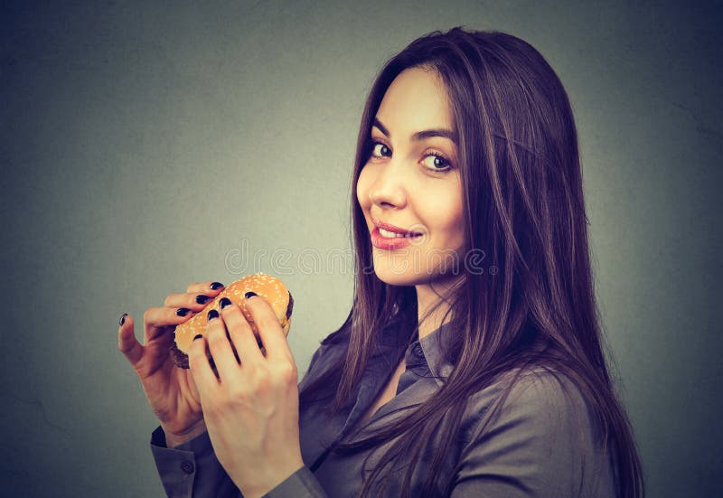 Милая женщина при cheeseburger смотря камеру стоковая фотография Милая женщина при cheeseburger смотря камеру стоковая фотография